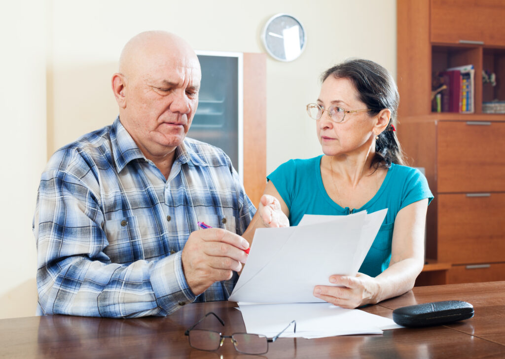 Senior couple reviewing Affordable Care Act health insurance documents at home.