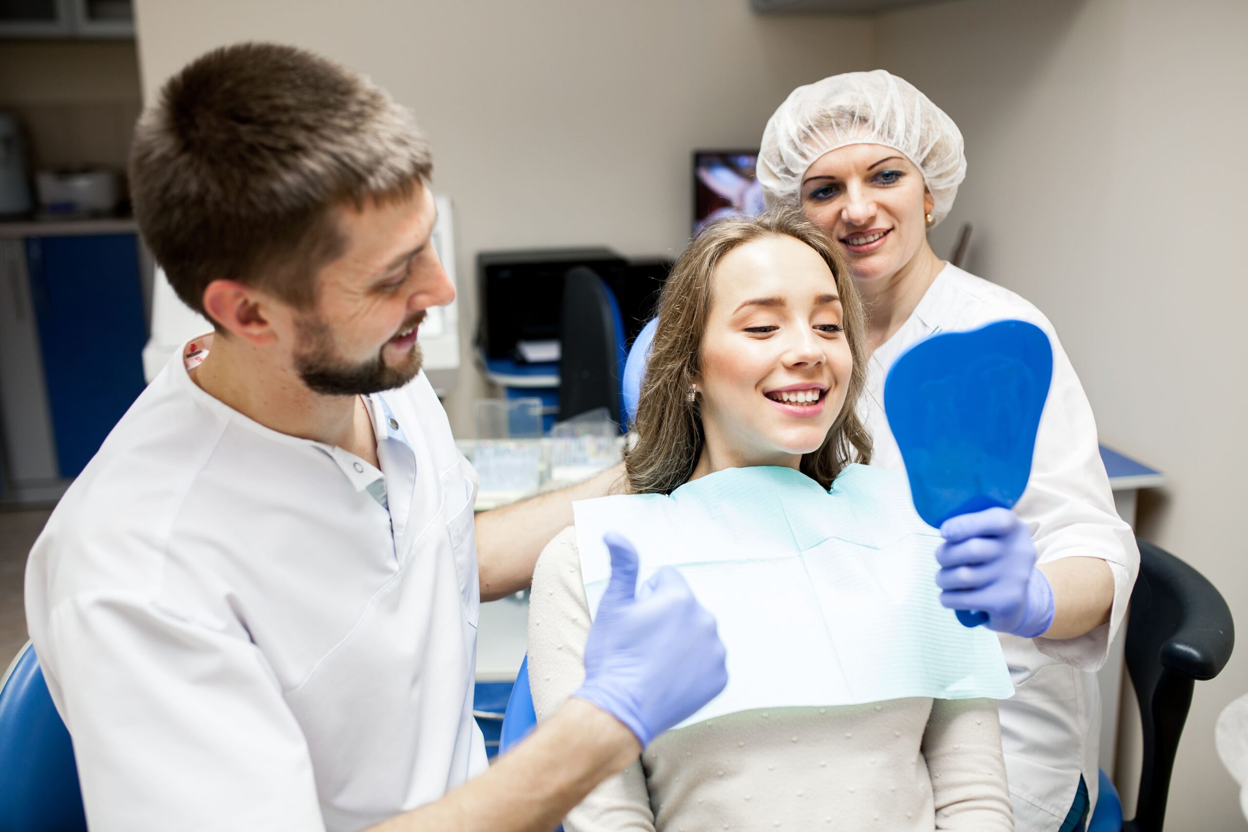 Dentist and assistant showing a female patient her smile in a dental clinic.