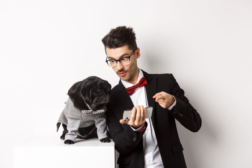 Man showing phone to dressed pug dog, explaining something—concept related to is aca dog bad and pet ownership concerns